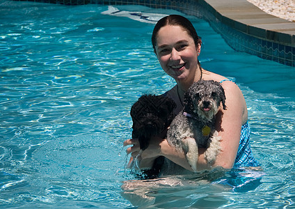女孩和两只狗在一个游泳池里图片