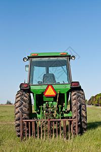绿色拖拉机在带蓝天的农场田地中图片