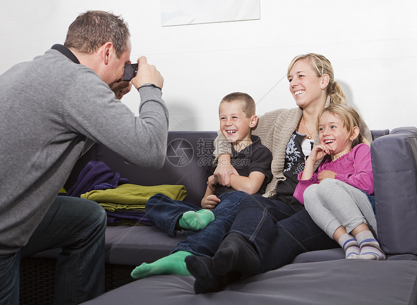 父亲给家人照了相团结享受母亲客厅女性相机家庭后代四个人沙发图片