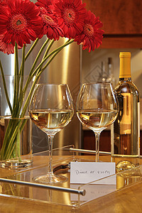 白葡萄酒的杯子和雪贝拉花菊图片
