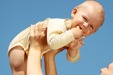 母亲在蓝天下怀着婴儿公园乐趣孩子幸福父母女性母性女孩家庭童年图片