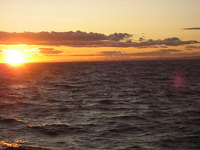 海上日落波浪天空晴天水手帆船绳索桅杆黄色红色游艇背景图片