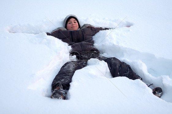 欢乐男孩在清雪中躺着微笑男生帽子青年孩子们投标童年喜悦说谎乐趣图片