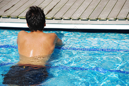 年轻人在游泳池的边缘放松了一下成人短裤闲暇蓝色泳池男性日光浴游泳水池酒店图片