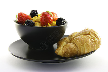 玉米片在黑碗里和一个Croissant午餐薄片营养谷物牛奶饮食食物蜂蜜水果面包图片