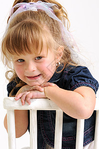 穿着蓝裙子的金发坐在白椅子上微笑眼镜女性童年孩子喜悦乐趣女孩孩子们快乐图片