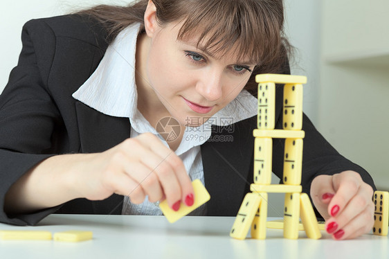 年轻妇女在桌子上建造多米诺骨骼塔图片