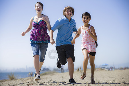 少年奔跑三个孩子跑在海滩上乐趣青少年幸福家庭海洋黑发男性女孩朋友们少年背景