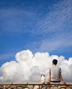 男人和狗坐在一起 看着夏天的云朵图片