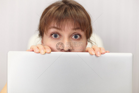 有趣的女孩躲在笔记本电脑屏幕后面图片