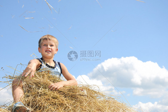 男孩坐在干草车上扔稻草图片