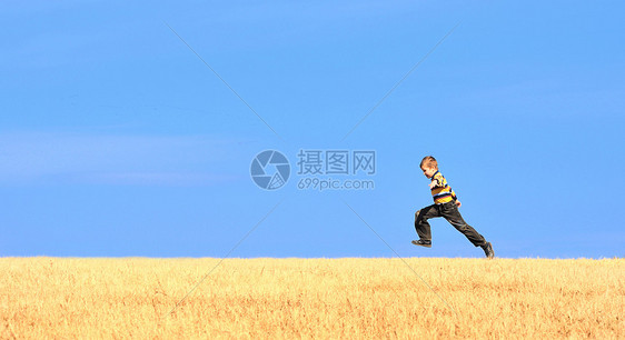 年轻男孩在田野上跳跃牛仔裤天空青年蓝色草地自由休闲幸福土地跑步图片