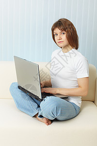 带笔记本电脑的年轻女孩坐在沙发上图片