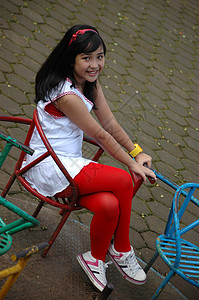 小女孩坐在公园里白色青年数字孩子们红色衬衫黑色女士身体未成年人图片