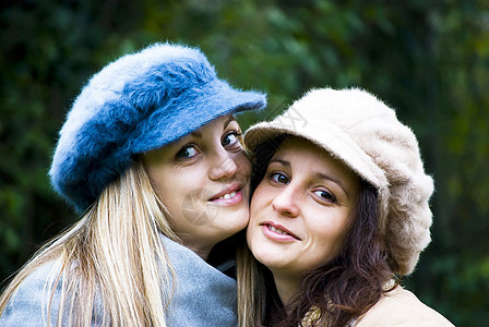 两个女孩玩得开心微笑蓝色幸福女性化帽子金发衣服女性黑发情感图片