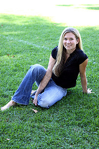 赤脚青年女子在草地上女士眼睛女性公园微笑头发金发白色牛仔裤女孩图片