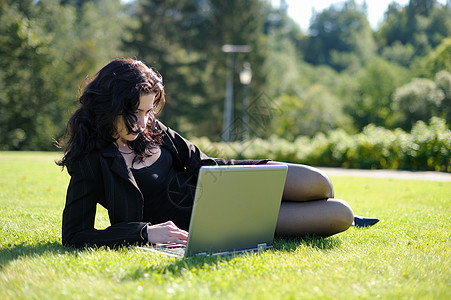 在公园里拿着笔记本的年轻女士黑发上网自由互联网头发商业工作通信移动全球图片