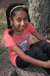 小女孩坐在树旁的树边眼睛黑色棕色数字未成年人身体绿色孩子们女性公园图片