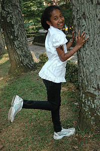 小女孩站在树旁 站起来绿色眼睛黑色衬衫未成年人棕色卷曲公园女士数字图片