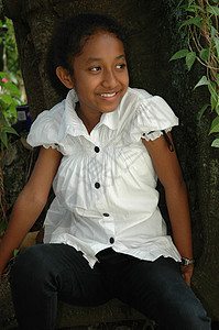 小女孩坐在树旁的树边棕色青年数字黑色身体白色绿色衬衫孩子们公园图片