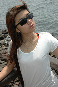 戴墨镜的年轻女士配饰岩石身体衬衫青年女孩牛仔裤海滩太阳镜黑色图片