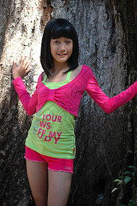可爱的姑娘站在树旁青年黑色未成年人数字孩子们衬衫眼睛身体粉色绿色图片