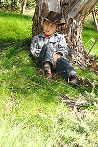 坐在树口香糖树下面的乡村男孩图片