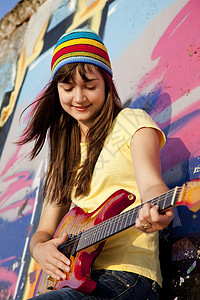 美丽的黑发美女 吉他和涂鸦墙在后院白色女性城市岩石乐趣帽子青少年艺术微笑音乐图片