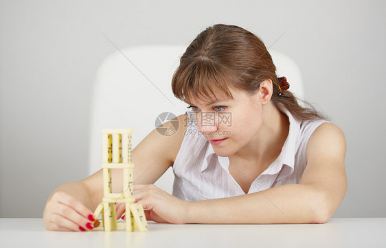 年轻女人从坐在桌上的多米诺人玩游戏图片