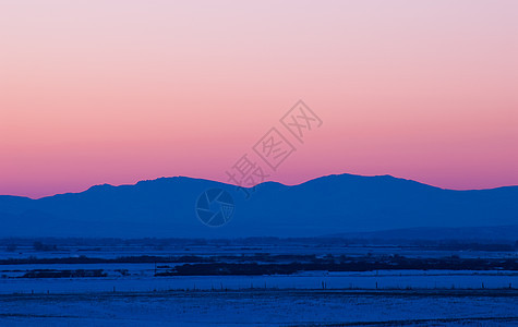 美国蒙大拿州加拉廷县Bozeman以北的冬季日落后 雪覆盖了田地和遥远的博尔德山脉图片