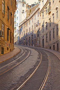 葡萄牙里斯本有电车铁轨的街道曲目运输鹅卵石有轨电车路面建筑物城市背景图片