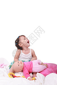 快乐的小宝贝女孩坐在床上 带着洋娃娃坐在床上图片