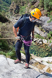 男人在瀑布下游绳索头盔极限男士悬崖勇气系统地形假期运动图片
