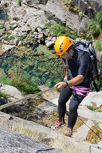 男人在瀑布下游行动峡谷系统假期地形边缘绳索男士极限冒险图片