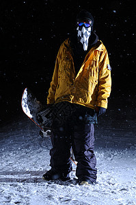 夜里站着的滑雪运动员的肖像滑雪者单板橙子夹克滑雪板下雪运动图片