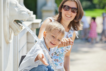 母亲和她儿子一起玩水公园蓝色快乐阳光乐趣女性男生婴儿后代头发图片