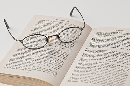 在开放书本上带有黑色四边框的眼镜乐器阅读眼睛验光师反射矫正阴影塑料玻璃喇叭背景图片