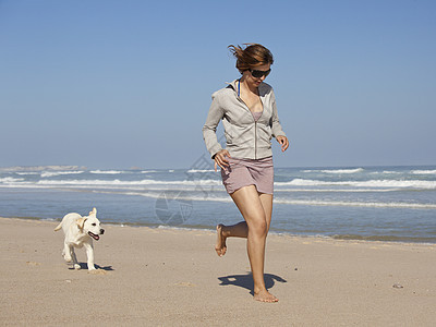 女孩带着可爱的狗宠物友谊朋友海岸人行道海滩跑步小狗闲暇乐趣图片