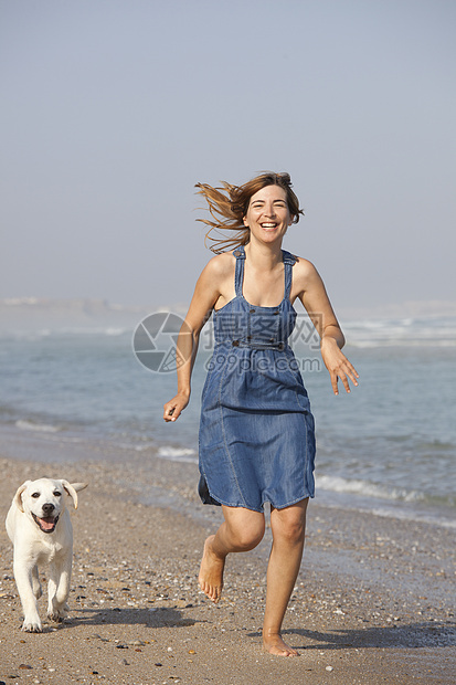 女孩带着她的狗动物海岸微笑闲暇跑步海洋猎犬宠物海滩朋友图片