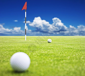 高尔夫球在背景中挂着旗子的绿色 非常浅的田地深度图片