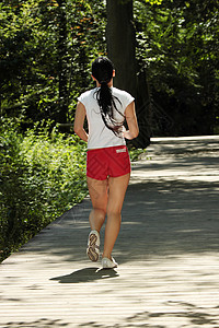 年轻女跑步青年运动装锻炼森林女士运动树木慢跑者成人火车闲暇图片