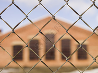在围栏后面建筑工业红色监狱锁定砖墙蓝天蓝色栅栏图片