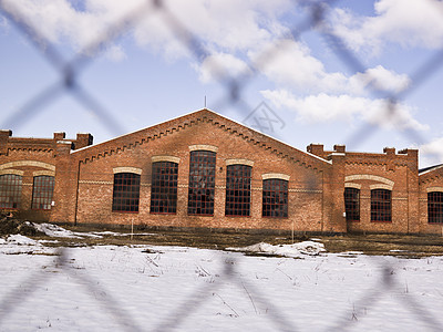 在围栏后面建筑红色栅栏锁定蓝色工业监狱蓝天砖墙图片