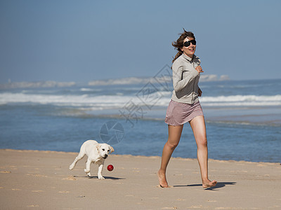 女孩带着可爱的狗猎犬人行道海洋朋友乐趣闲暇海滩动物微笑幸福图片