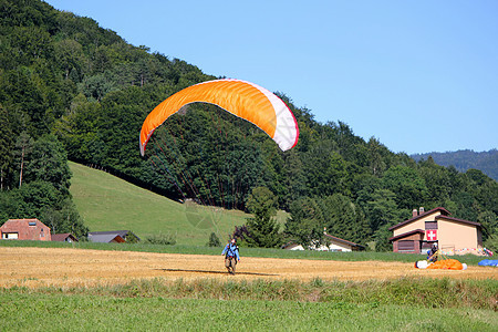 降落在田野的滑翔伞山脉降落伞天空马具探索自由土地空气运动橙子图片