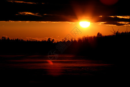 太阳落在一个冰冻的萨斯喀彻温湖后面风景美术大草原乡村水平剪影树木旅行图片