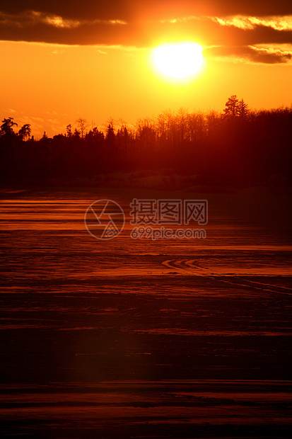 太阳落在一个冰冻的萨斯喀彻温湖后面乡村剪影树木大草原风景美术旅行图片