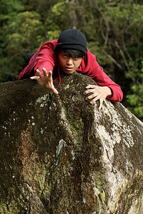 身穿红毛衣和大豆的亚洲中国男子在岩石上伸展手臂图片