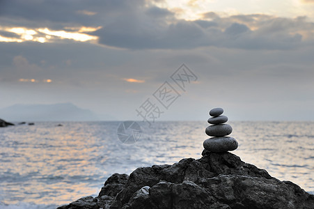 戏剧性天空背景的石头和石块平衡卵石想像力温泉假期岩石边缘日落海景海滩图片