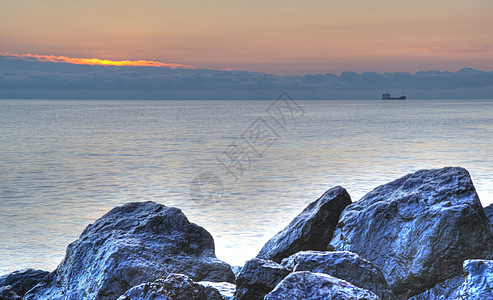 夜间的海岸线和山岳薄雾日落边缘假期卵石阳光风景天空海浪石头图片